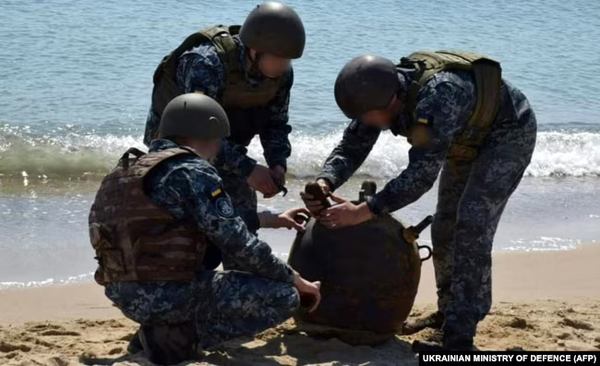 Українські військові знешкоджують морську міну, викинуту на берег штормом, під час масштабного вторгнення Росії до України, травень 2022 року